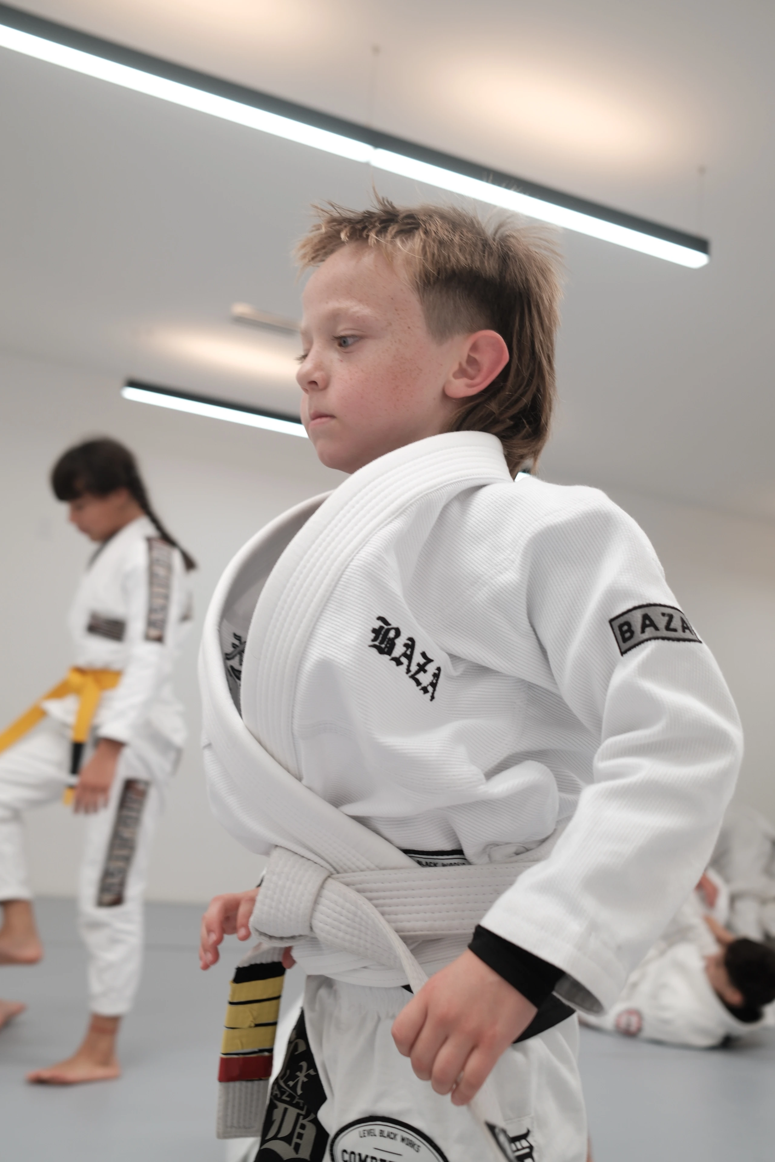 Focused young student in BAZA gi during youth BJJ class